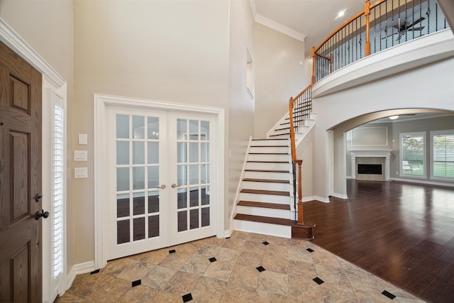 entryway with hardwood / wood-style floors, ornamental molding, a high ceiling, and french doors