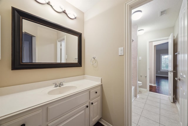 bathroom with toilet, a textured ceiling, vanity, and tile patterned floors