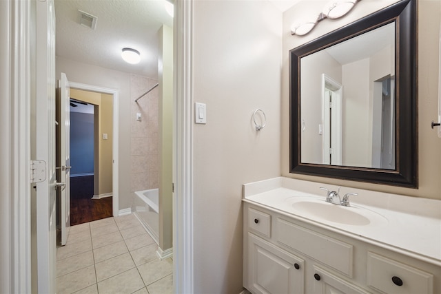 bathroom featuring vanity, tiled shower / bath, a textured ceiling, and tile patterned floors