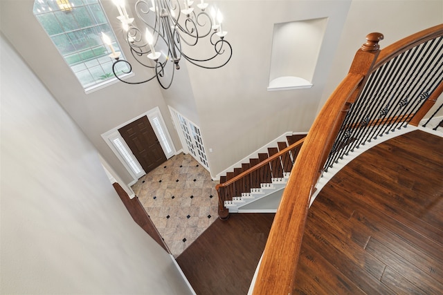 foyer entrance featuring a notable chandelier, hardwood / wood-style flooring, and a towering ceiling