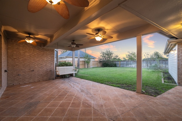 patio terrace at dusk with a yard and ceiling fan