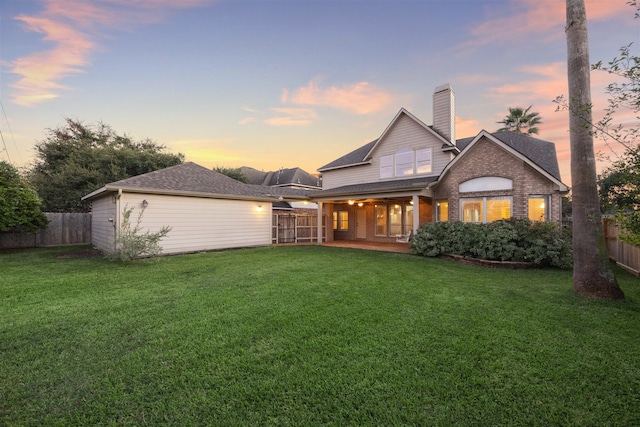 back house at dusk with a lawn