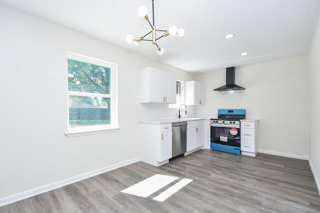 kitchen with appliances with stainless steel finishes, tasteful backsplash, white cabinetry, wood-type flooring, and wall chimney range hood