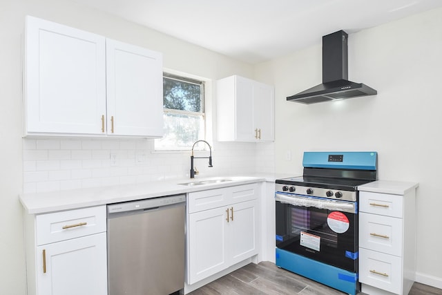 kitchen featuring wall chimney range hood, stainless steel appliances, sink, and white cabinets