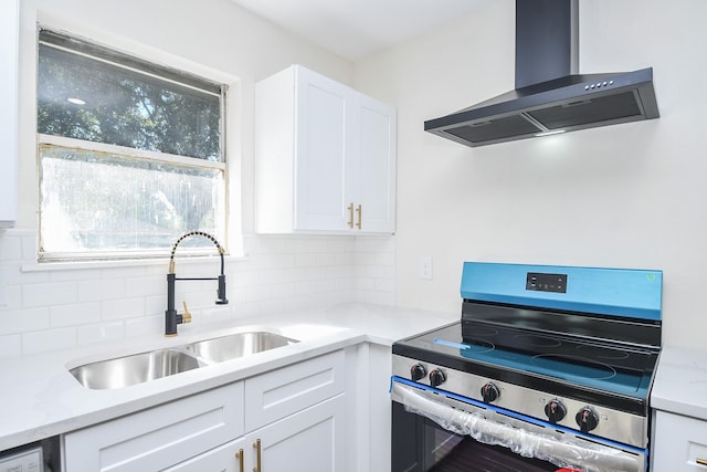 kitchen with white cabinetry, sink, decorative backsplash, wall chimney range hood, and electric stove