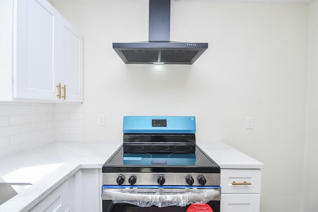 kitchen with white cabinetry, light stone counters, island range hood, and stainless steel electric stove