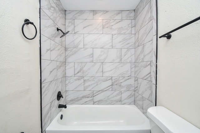 bathroom featuring tiled shower / bath combo and toilet