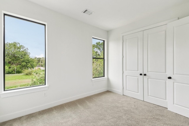 unfurnished bedroom with light carpet and a closet