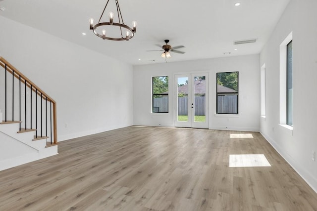 unfurnished living room featuring ceiling fan with notable chandelier, french doors, and light wood-type flooring