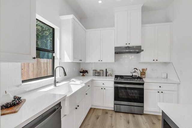 kitchen featuring white cabinetry, light stone countertops, tasteful backsplash, light hardwood / wood-style floors, and appliances with stainless steel finishes