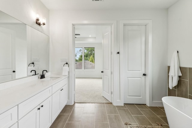 bathroom featuring tile patterned flooring, vanity, and a bath