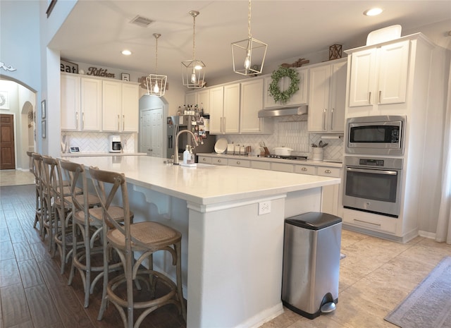 kitchen featuring white cabinetry, appliances with stainless steel finishes, and an island with sink