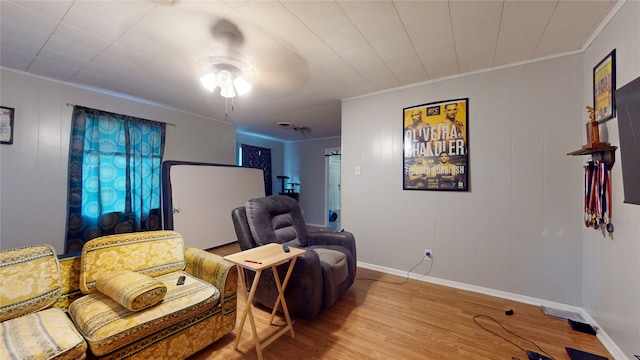 living area featuring crown molding, light hardwood / wood-style floors, and ceiling fan