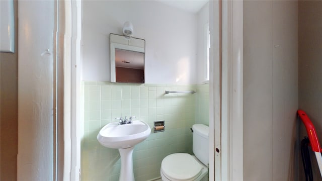 bathroom with toilet and tile walls