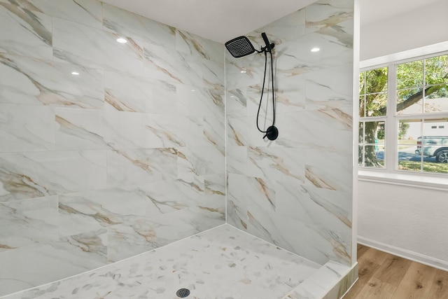 bathroom with a tile shower and wood-type flooring