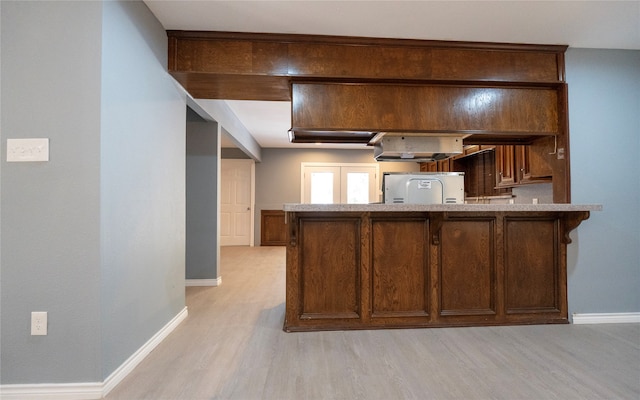 kitchen with light hardwood / wood-style floors, kitchen peninsula, and white refrigerator