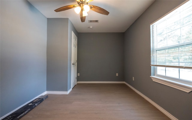 spare room with ceiling fan, wood-type flooring, and a wealth of natural light