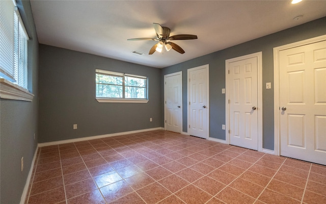 unfurnished bedroom featuring multiple closets, tile patterned flooring, and ceiling fan