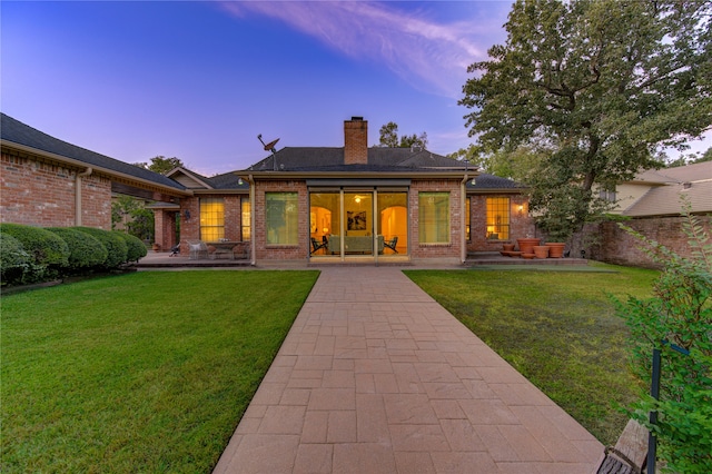 back house at dusk featuring a yard