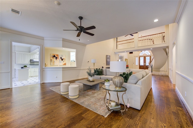 living room featuring dark wood-type flooring, ceiling fan, and crown molding