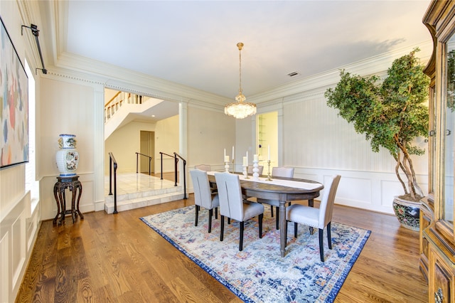 dining area with ornamental molding, hardwood / wood-style flooring, and an inviting chandelier