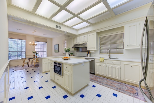 kitchen with stainless steel appliances, a notable chandelier, pendant lighting, sink, and a center island