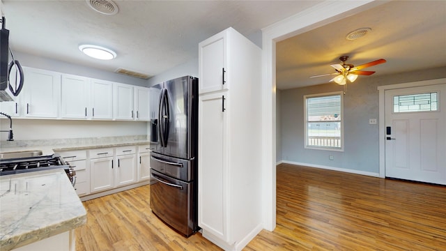 kitchen featuring light hardwood / wood-style flooring, stainless steel fridge, white cabinetry, light stone counters, and ceiling fan