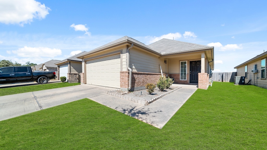 view of front of property with a front yard, central AC unit, and a garage