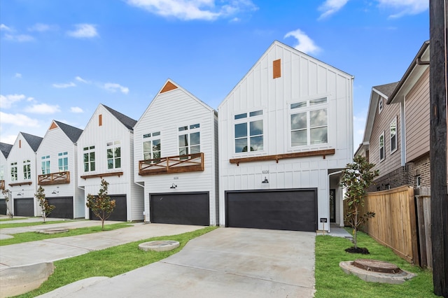 view of front of home featuring board and batten siding, driveway, an attached garage, and fence