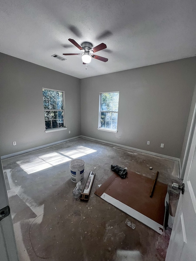 empty room with ceiling fan and a textured ceiling