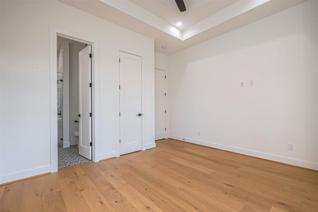 unfurnished bedroom featuring recessed lighting, baseboards, ensuite bathroom, and light wood-type flooring