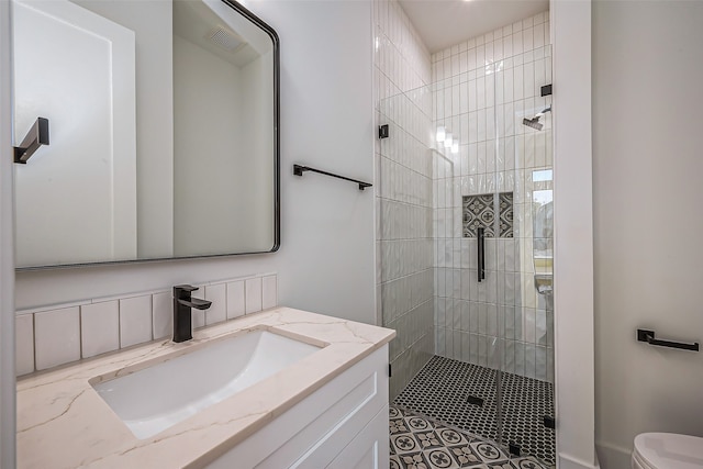 bathroom with vanity, a tile shower, and toilet