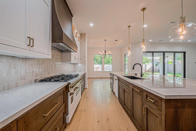 kitchen with double oven range, a sink, premium range hood, light wood finished floors, and recessed lighting