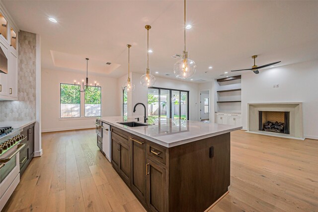 kitchen with dark brown cabinets, a sink, light wood-style floors, light countertops, and high end range