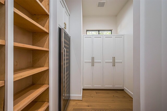 spacious closet with visible vents, light wood-style flooring, and wine cooler