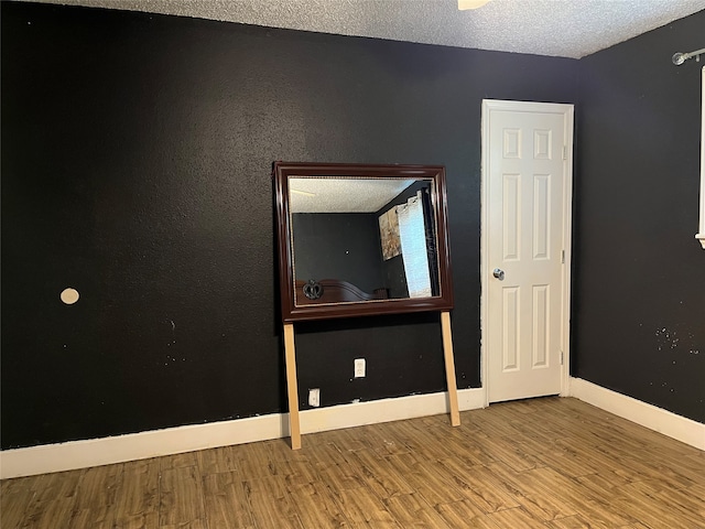 unfurnished room featuring wood-type flooring and a textured ceiling