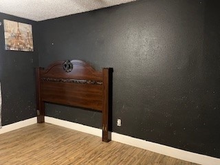 unfurnished bedroom with a textured ceiling and wood-type flooring