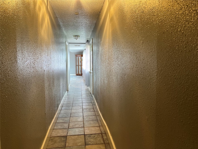 hallway featuring a textured ceiling and light tile patterned flooring