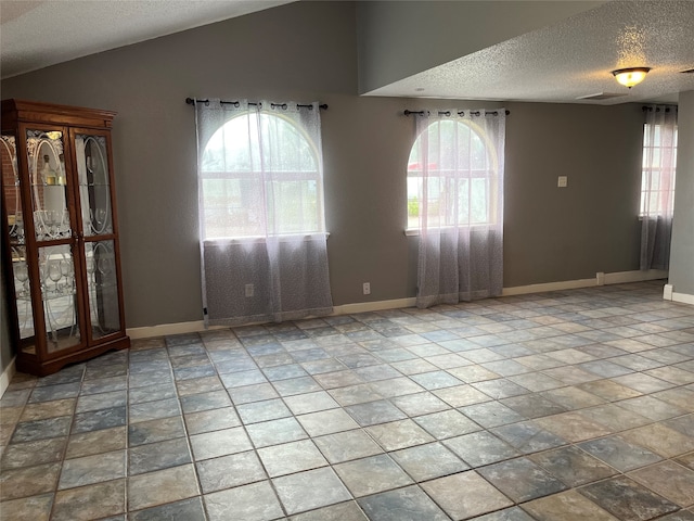 spare room featuring a textured ceiling, vaulted ceiling, and plenty of natural light