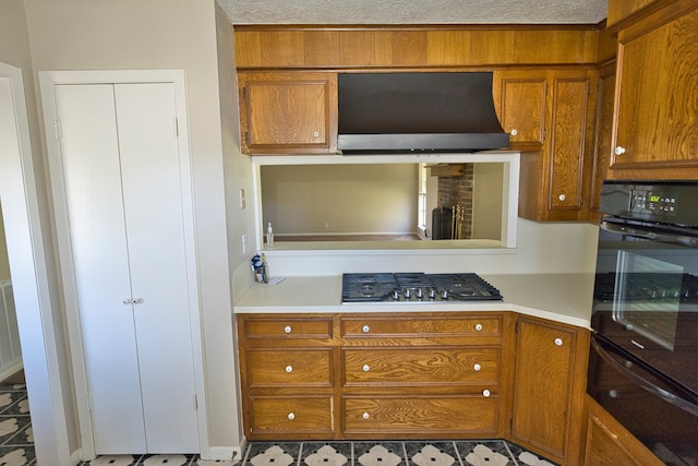 kitchen featuring range hood, stainless steel gas cooktop, and a textured ceiling