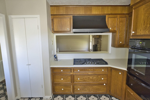 6823 County Road 659, Brazoria, TX 77422 - kitchen featuring a warming drawer, range hood, stainless steel gas stovetop, black oven, and brown cabinets