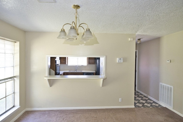 6823 County Road 659, Brazoria, TX 77422 - kitchen with a chandelier, carpet floors, a textured ceiling, and hanging light fixtures