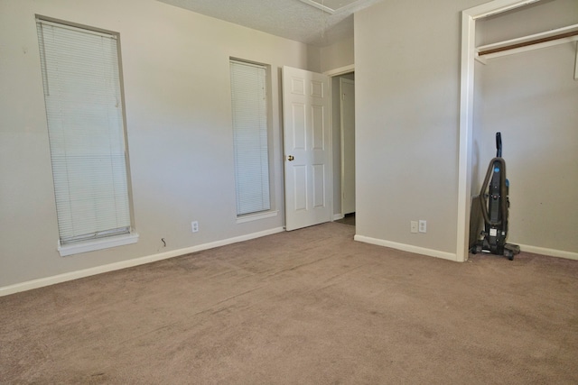 unfurnished bedroom with a textured ceiling and light colored carpet