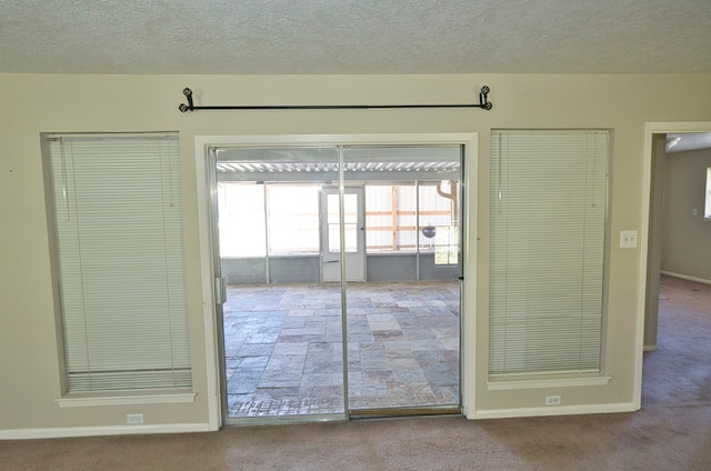 doorway to outside with a textured ceiling and carpet flooring