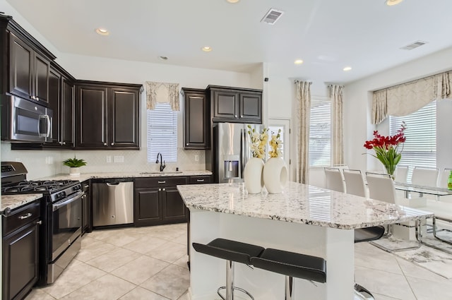 kitchen featuring a center island, appliances with stainless steel finishes, sink, and a breakfast bar area