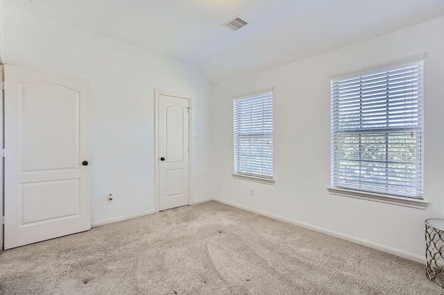 spare room with lofted ceiling, light carpet, and plenty of natural light