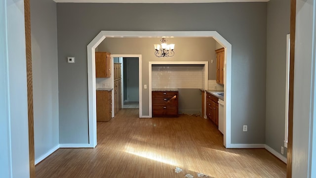 hallway featuring a chandelier and light hardwood / wood-style flooring