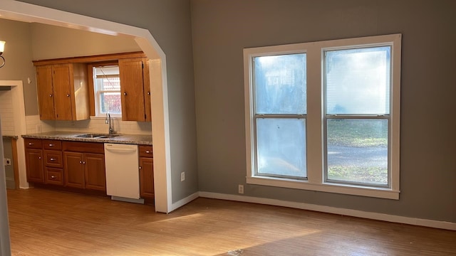 kitchen with sink, backsplash, white dishwasher, light stone counters, and light hardwood / wood-style flooring