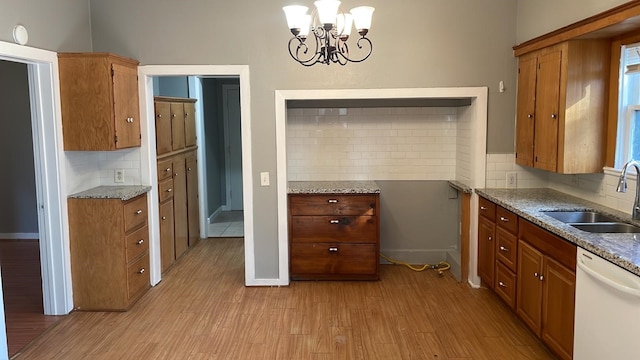 kitchen with decorative backsplash, dishwasher, light hardwood / wood-style floors, a notable chandelier, and sink