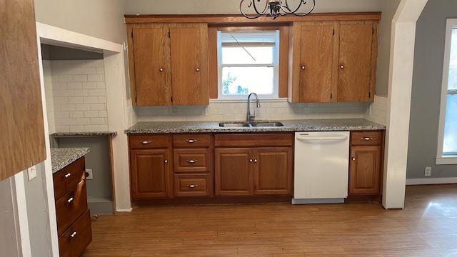 kitchen with tasteful backsplash, white dishwasher, sink, and light wood-type flooring